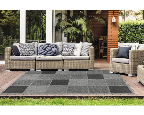 Outdoor-Szene mit einem grau karierten Teppich und Rattansitzmöbeln auf einer Terrasse