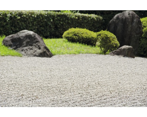Gros plan d''un jardin zen avec du gravier, des pierres et des plantes vertes