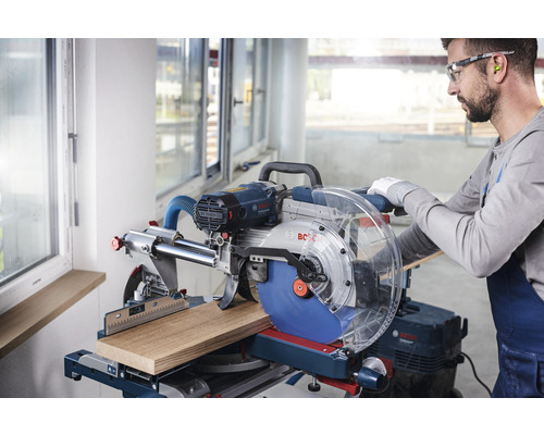 Un homme utilise une scie à onglet radiale Bosch pour couper une pièce de bois.