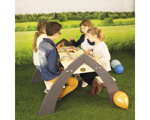 Des enfants sont assis à une table de jeu pour enfants à l''extérieur