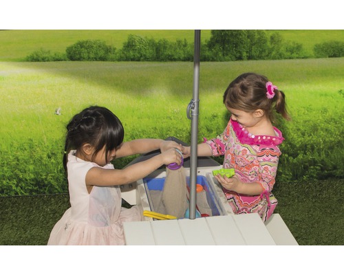 Zwei Kinder spielen an einem Sand- und Wassertisch mit Sonnenschirm im Garten.