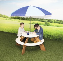 Des enfants sont assis à une table de pique-nique ronde avec un parasol dans le jardin.