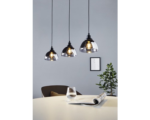 Drei Pendelleuchten aus Glas über einem Esstisch.