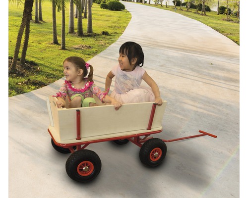 Zwei Kinder sitzen in einem Bollerwagen auf einem Gartenweg.