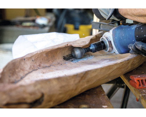 Handwerker bearbeitet eine hölzerne Schale mit einer Schleifmaschine.