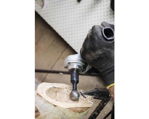 Eine Person verwendet eine Schleifkugel an einem Holzstück mit einem Elektrowerkzeug.