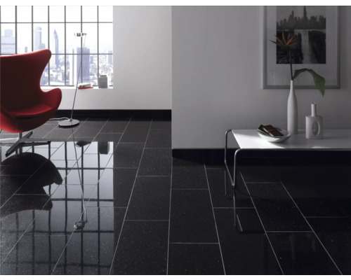 Wohnraum mit glänzend schwarzen Bodenfliesen, Sessel, Tisch und Fenster