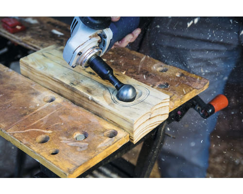 Mann bearbeitet Holz mit Rotationsfräse und Kugelkopf