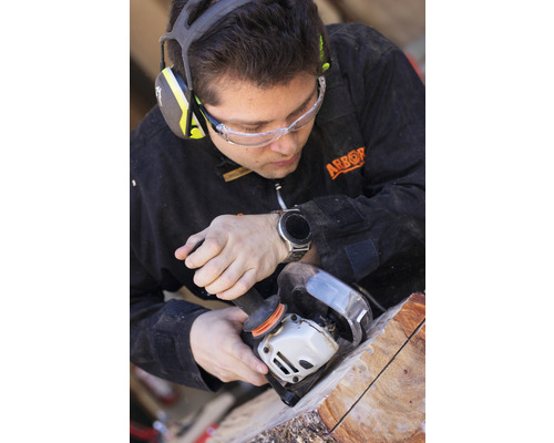 Handwerker bearbeitet Holz mit Winkelschleifer, geschützt durch Sicherheitsausrüstung