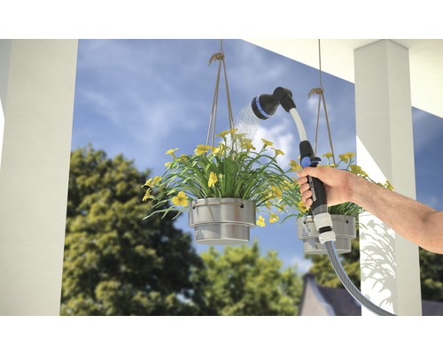 Une personne arrose des jardinières suspendues avec un pistolet d''arrosage.