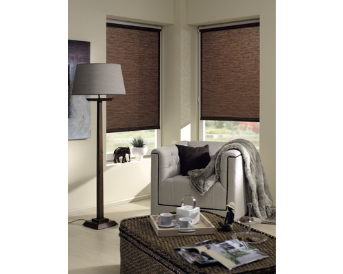 Wohnzimmer mit braunen Rollos an den Fenstern, Sessel, Stehlampe und Tisch