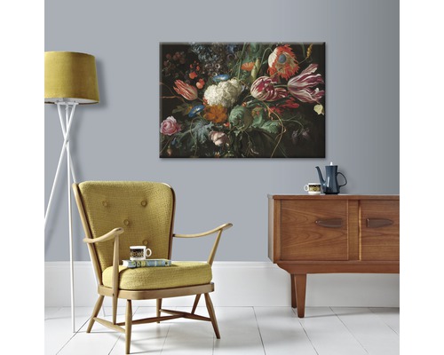 Gemäldedruck mit Blumenarrangement über einem Holzbuffet mit Sessel und Stehlampe
