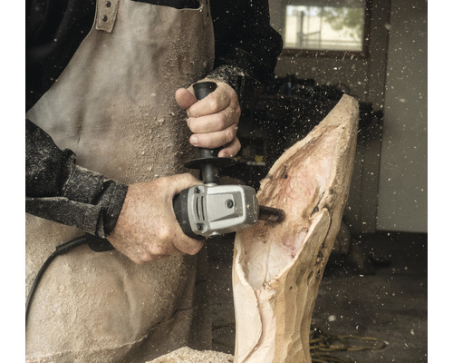 Mann benutzt Kettensägenschnitzer zum Bearbeiten eines Holzstücks