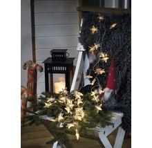 Scène décorative avec guirlande lumineuse en forme d''étoiles, lanterne et gnome sur un tabouret.