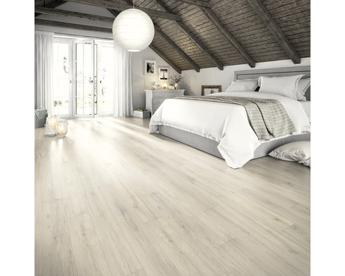 Pièce lumineuse avec lit et parquet en bois clair.