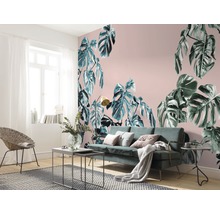 Salon avec papier peint motif Monstera, canapé et fauteuil en rotin.