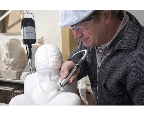 Un homme travaille sur une sculpture en marbre avec un outil multifonction Dremel.
