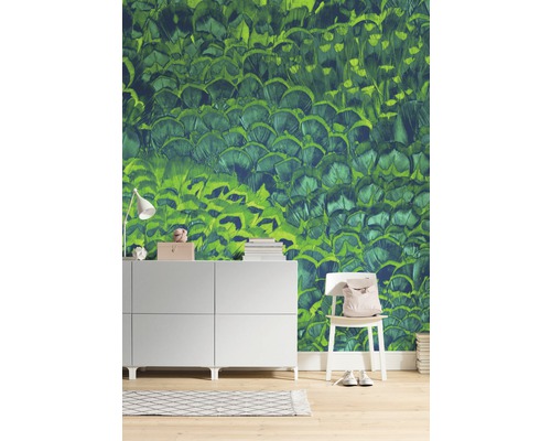 Salon avec papier peint vert à motif de plumes, commode et chaise