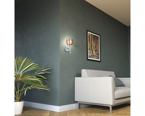 Wohnzimmer mit Wandleuchte, Sofa und Zimmerpflanze.