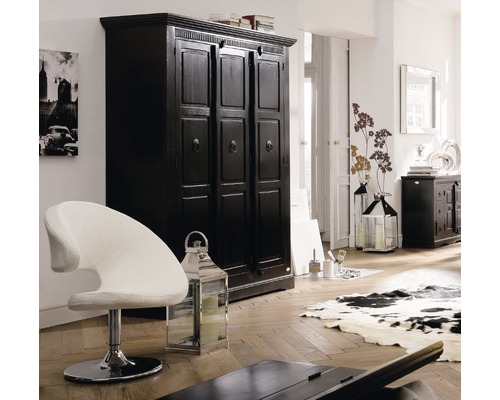 Scène d''intérieur avec une armoire noire, un fauteuil blanc et des lanternes décoratives dans une pièce lumineuse.