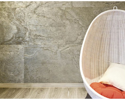 Wandgestaltung mit Steinpaneelen und Korbsessel mit Kissen auf Holzboden