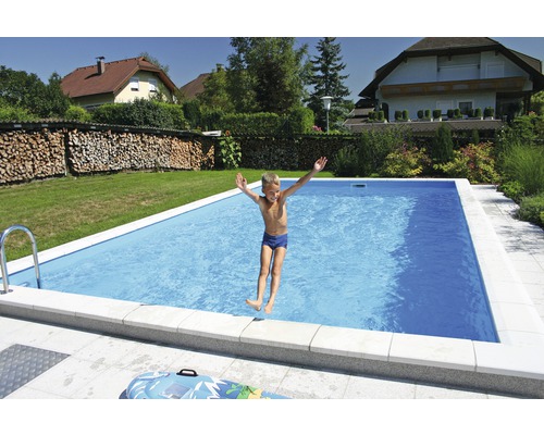Ein Junge springt in einen rechteckigen Pool im Garten.