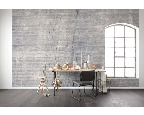Intérieur avec mur en béton gris, bureau, chaise et grande fenêtre pour une ambiance lumineuse et moderne.