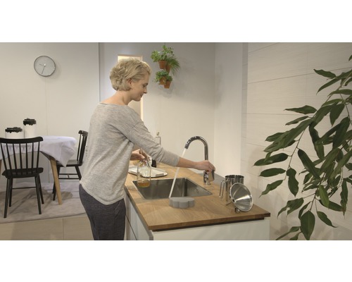 Helle Küche mit Frau am Waschbecken, Armatur, Spüle und Küchenutensilien.