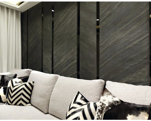 Wohnzimmer mit grauer Steinwand und hellgrauem Sofa