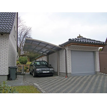 Carport et garage en pierre avec allée pavée et voiture garée