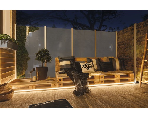 Salon d''extérieur confortable avec meubles de palettes, coussins et éclairage pour jardin ou terrasse.