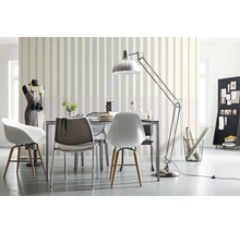 Salon avec table à manger, chaises, lampadaire et papier peint rayé pour une ambiance claire et organisée.