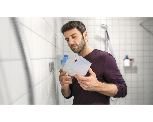 Un homme tient une étagère de douche transparente dans la salle de bains.