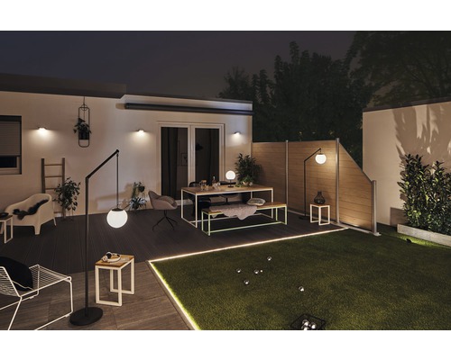 Jardin éclairé avec clôture de jardin, pelouse, coin salon et lampadaires