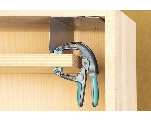 Une serre-joint à une main fixe une pièce sur un meuble.