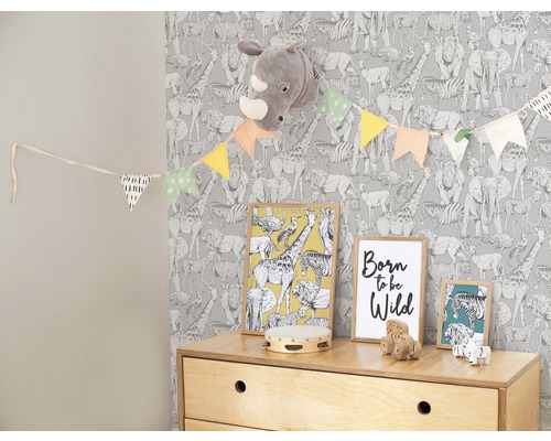 Chambre d''enfant avec papier peint à motifs animaliers, guirlande, images et commode à jouets.