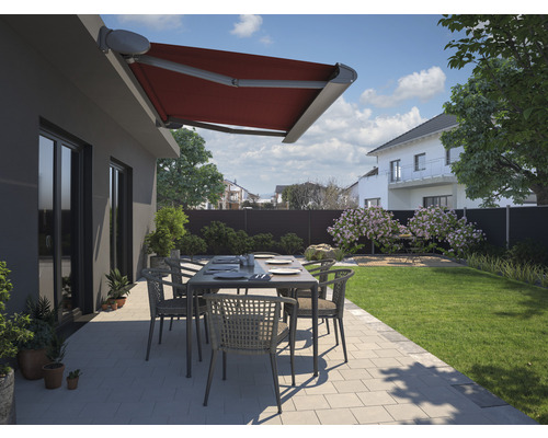 Terrasse avec store banne rouge, table de jardin et chaises dans un jardin résidentiel