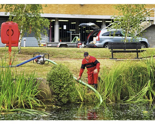 Homme avec pompe à eau au bord de l''étang pour travaux de drainage.