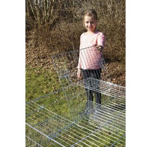 Mädchen hält ein Gitterelement eines Kleintiergeheges im Garten