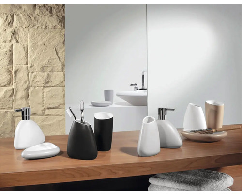 Scène de salle de bains avec divers accessoires de salle de bains sur une étagère en bois devant un miroir et un mur en pierre