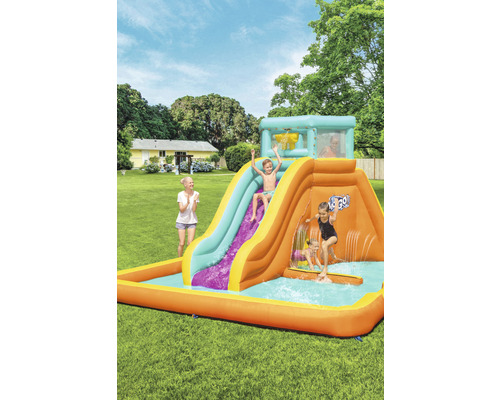 Aufblasbare Wasserrutsche mit Pool im Garten mit spielenden Kindern.