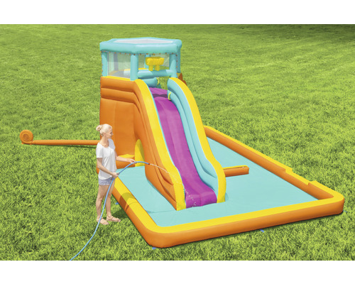 Aufblasbare Wasserrutsche mit Pool und Dame mit Wasserschlauch im Garten