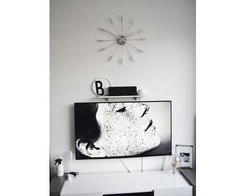 Wohnzimmer mit Fernseher, Wanduhr und Dekorationen auf einem Schrank