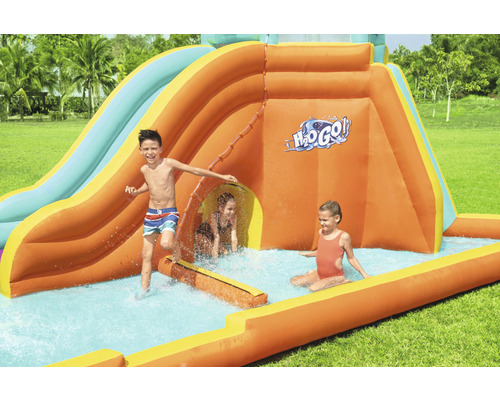 Aufblasbare Wasserrutsche mit spielenden Kindern im Garten.