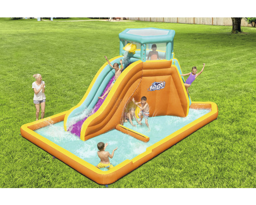 Aufblasbare Wasserrutsche mit Planschbecken und spielenden Kindern im Garten.