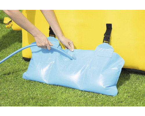 Person befüllt Wassersack zur Beschwerung einer Hüpfburg mit einem Wasserschlauch