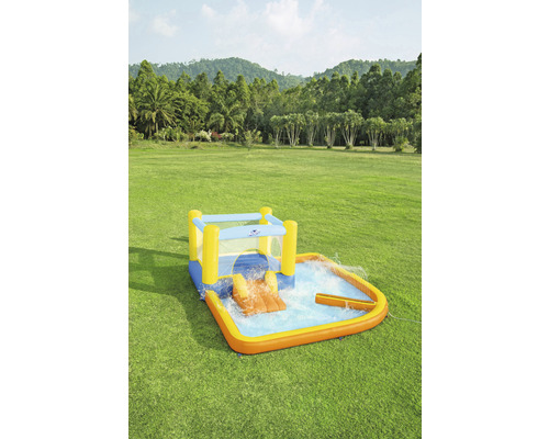 Aufblasbarer Kinderpool mit Rutsche und Wassersprinkler auf einer grünen Wiese.