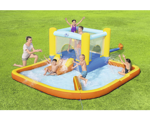 Aufblasbarer Wasserpark mit Rutsche und Planschbecken im Garten mit spielenden Kindern.