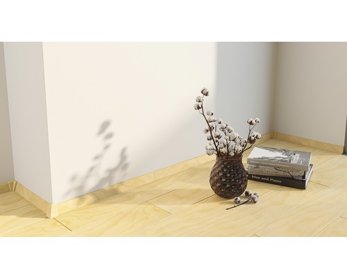 Scène décorative avec vase, branches de coton et livres sur plancher en bois.