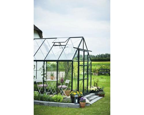 Serre avec portes en verre et mobilier de jardin dans le jardin